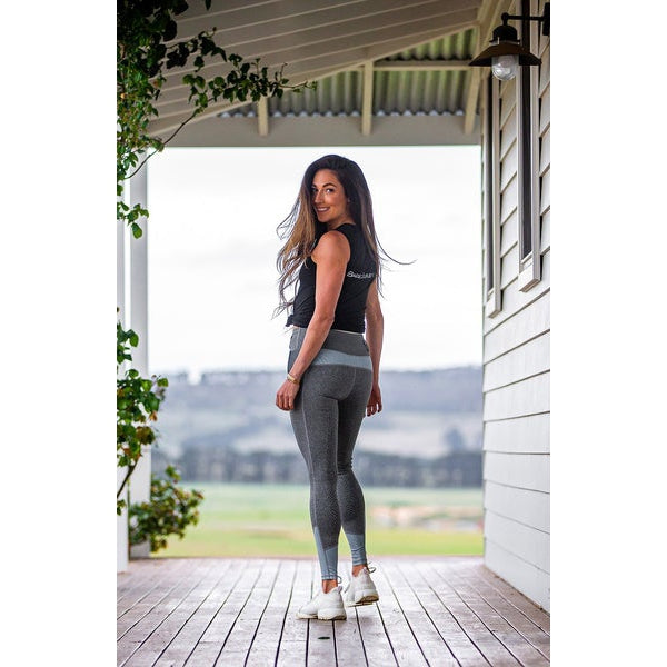 Woman standing on porch wearing gray horse riding tights.