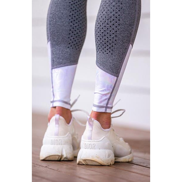 Person wearing gray horse riding tights and white sneakers standing.