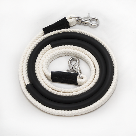 Coiled white and black horse riding reins with metal clips.