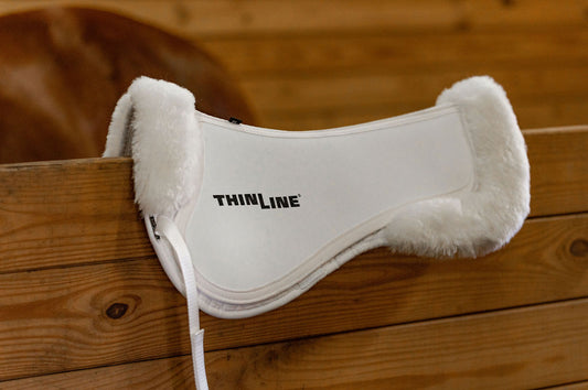 White Thinline saddle pad with fur edges on fence.